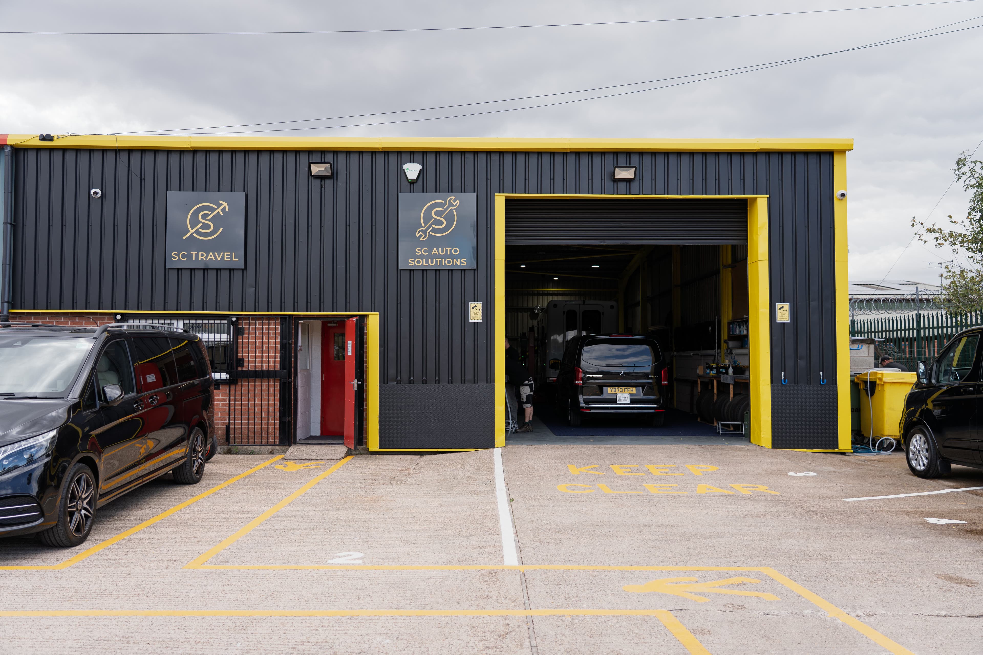 The SC Automotive Solutions workshop front, roller door open with vehicles inside